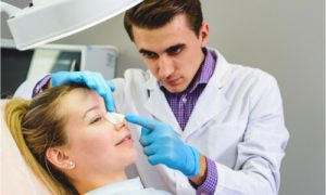 The doctor puts a nose splint on the patient's nose.